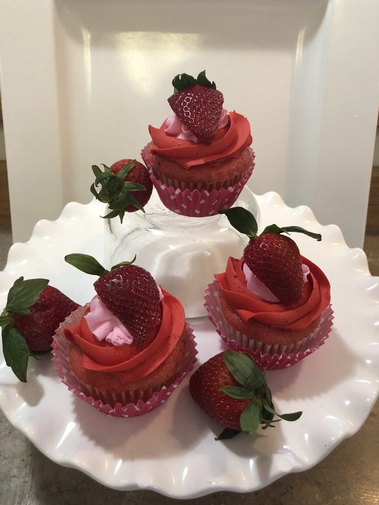 A white plate topped with three strawberry cupcakes.