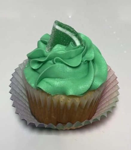 A cupcake with green frosting and candy on top.