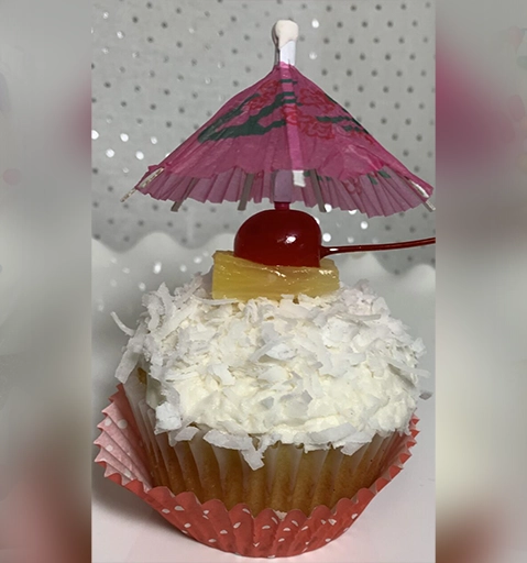 A cupcake with coconut frosting and an umbrella.