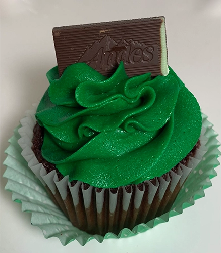 A cupcake with green frosting and chocolate bar.