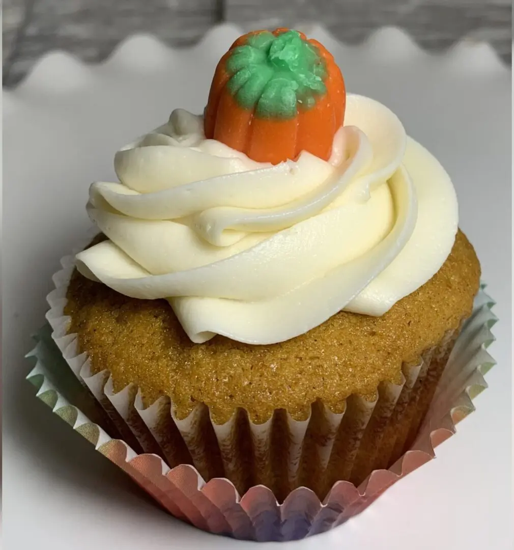 A cupcake with white frosting and a pumpkin on top.